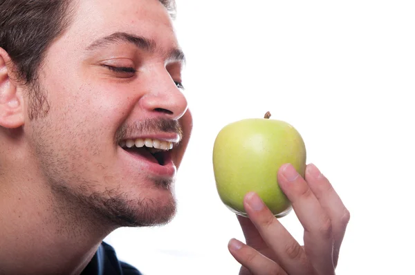 Joven macho comiendo manzana verde y sosteniendo en su mano — Foto de Stock