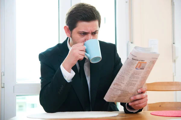 Uomo d'affari che fa colazione e legge giornali — Foto Stock
