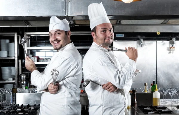 Retrato de dois chefs sorrindo e segurando utensílio de cozinha Imagens De Bancos De Imagens Sem Royalties