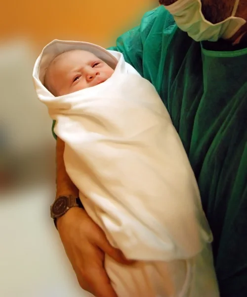 Доктор держит новорожденного ребенка — стоковое фото