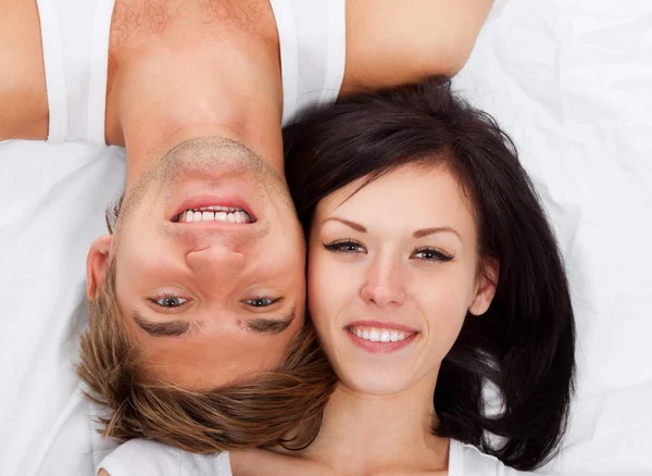 Jovem casal adorável deitado em uma cama — Fotografia de Stock