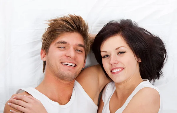Jovem casal adorável deitado em uma cama — Fotografia de Stock