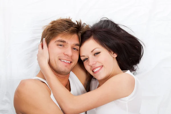 Joven pareja encantadora acostada en una cama — Foto de Stock