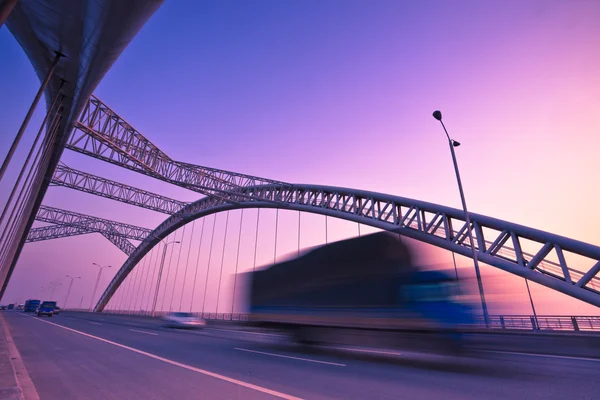 Φορτηγό με υπερβολική ταχύτητα μέσα από μια γέφυρα στο ηλιοβασίλεμα, κίνηση θάμπωμα. — Φωτογραφία Αρχείου