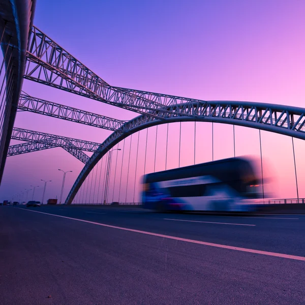 Caminhão acelerando através de uma ponte ao pôr do sol, borrão de movimento . — Fotografia de Stock
