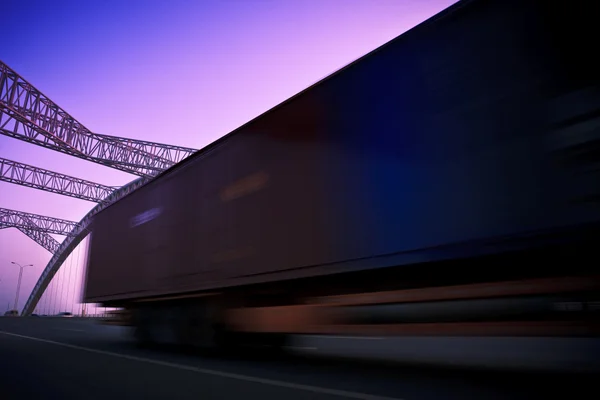 Грузовик проезжает через мост на закате, движение размыто . — стоковое фото
