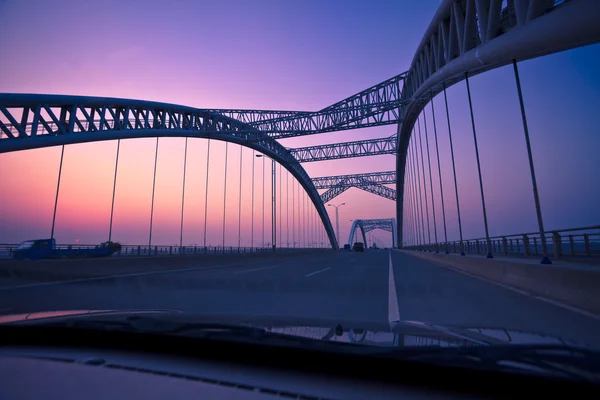 Teherautó gyorshajtás keresztül egy híd, a naplemente, motion blur. — Stock Fotó