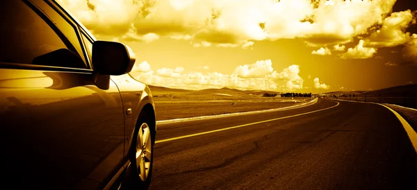 El coche en la carretera con el fondo de la pradera . — Foto de Stock