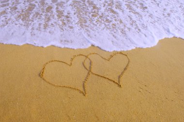 Two hearts drawn in beach in sunset clipart