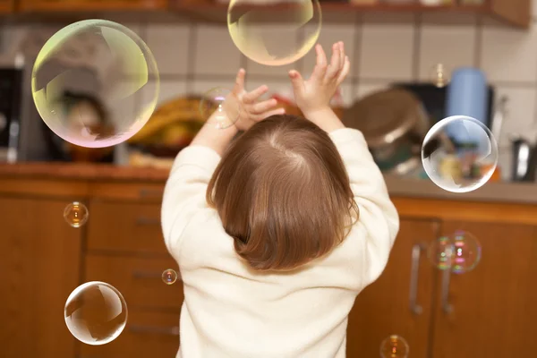 Malá dívka hraje s mýdlové bubliny — Stock fotografie
