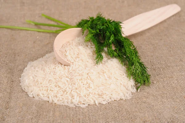 Рис с укропом и ложкой на холсте — стоковое фото