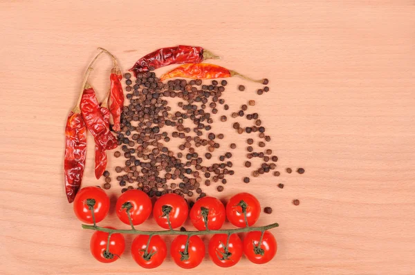 Pimienta negra pimiento rojo y tomate en la tabla de cortar de madera — Foto de Stock