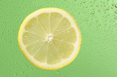 Yeşil arka planda bir sürü su damlası olan limon