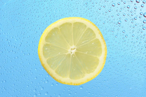 与许多水滴在蓝色背景上的柠檬 — 图库照片
