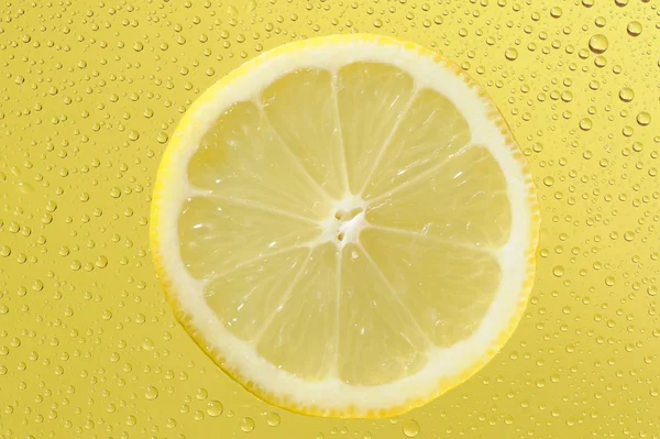 Limón con muchas gotas de agua sobre el fondo amarillo — Foto de Stock