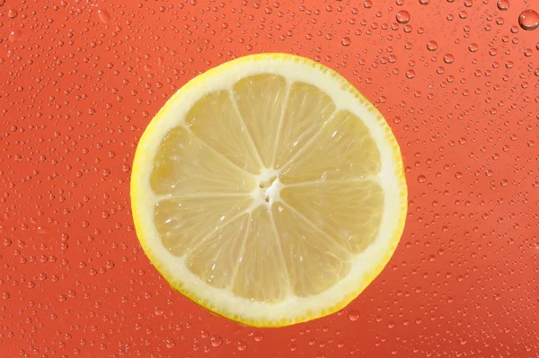 Limone con molte gocce d'acqua sullo sfondo rosso — Foto Stock