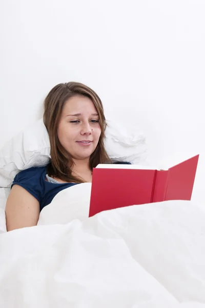 Nainen lukemassa sängyssä — kuvapankkivalokuva