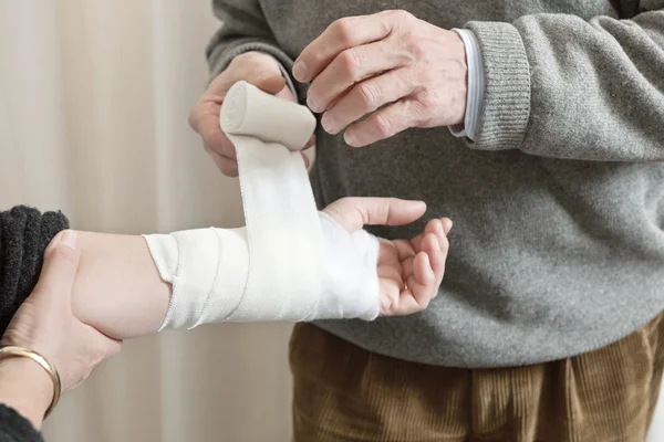 Doctor aplicando vendaje en la mano lesionada — Foto de Stock