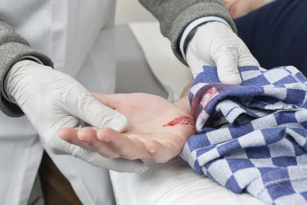 Doktor čištění krvácející řez tkaninou — Stock fotografie