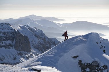 Man climbing a peak with snowboard clipart