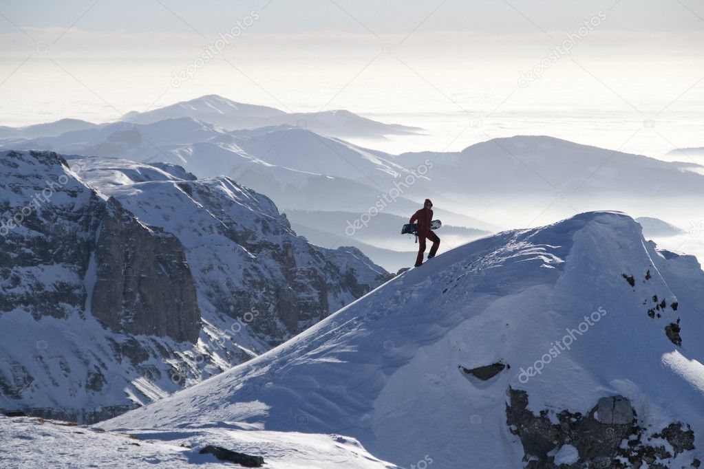 Man climbing a peak with snowboard