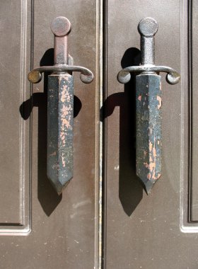 A fragment of metal doors with handles in the form of daggers clipart