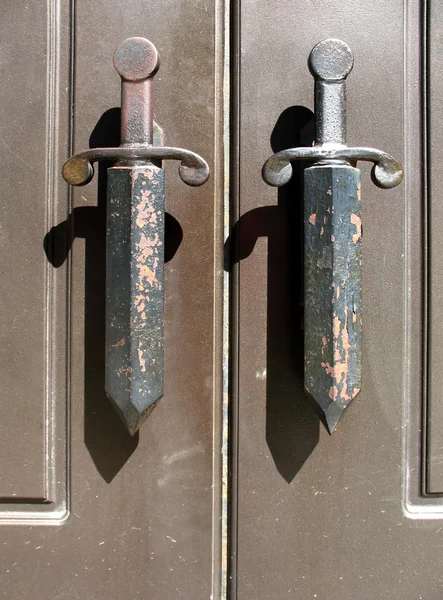 Een fragment van metalen deuren met handvatten in de vorm van dolken — Stockfoto