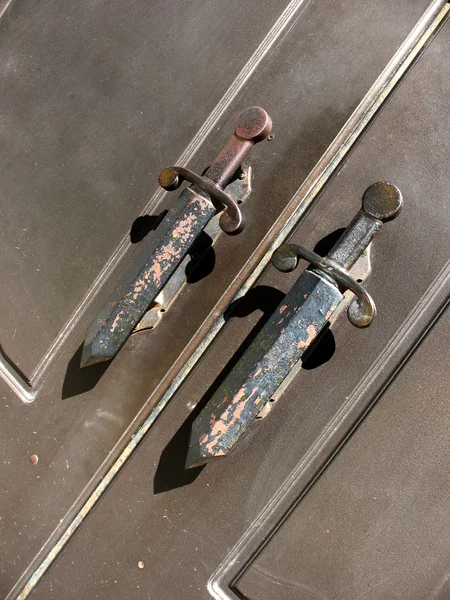 A fragment of metal doors with handles in the form of daggers — Stock Photo, Image