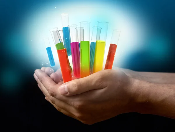 Different laboratory glassware with color liquid on hands — Stock Photo, Image