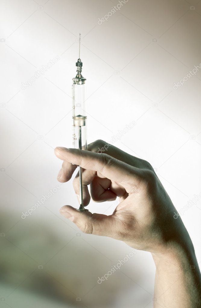 Old glass syringe in hand. Shallow DOF.