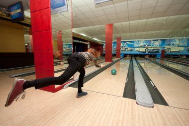 Funny beginner girl playing bowling clipart