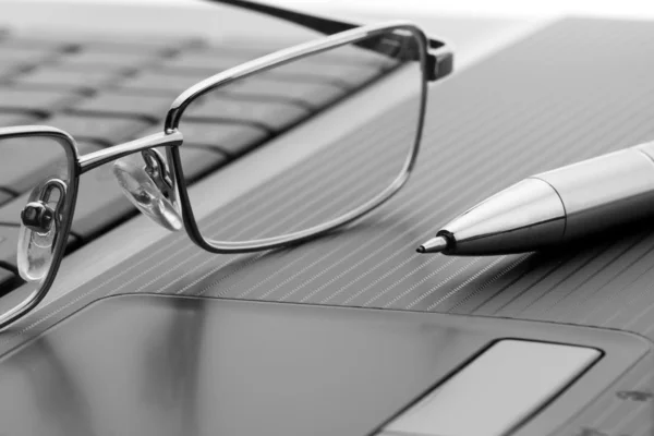 Óculos e caneta no laptop — Fotografia de Stock
