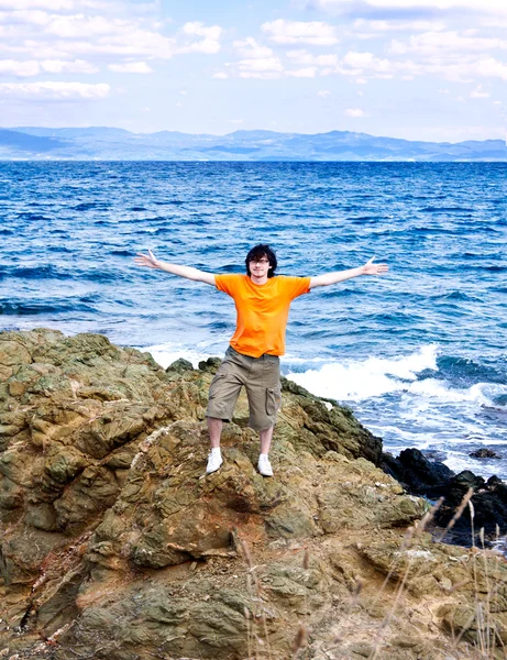 Den unge mannen vid havet på en sten — Stockfoto
