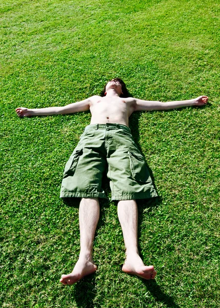 Der junge Mann ruht sich auf einem Gras aus — Stockfoto