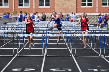 Teen Girls Competing in High School Hurdles Race clipart