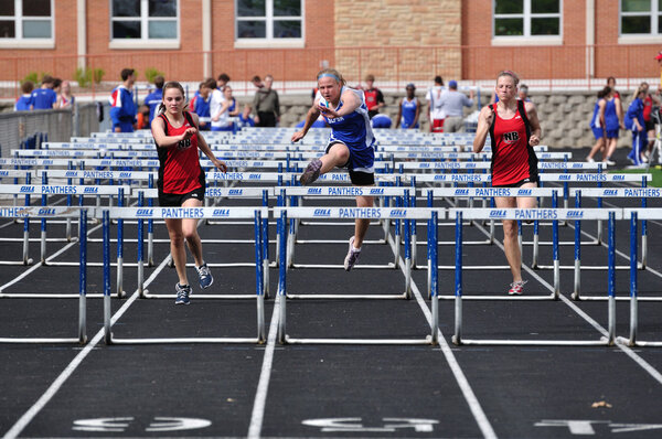 Teen Girls Competing in High School Hurdles Race