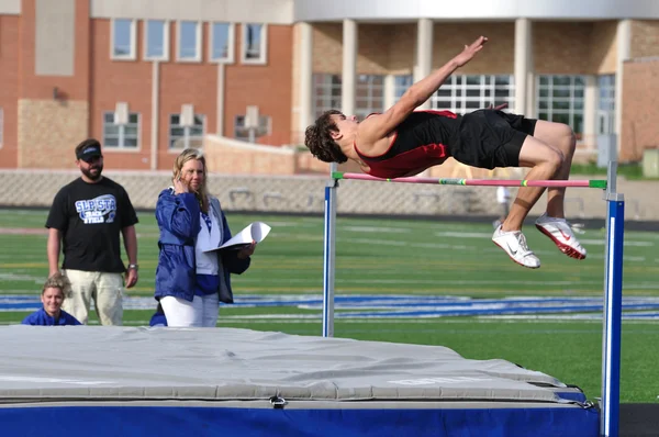 Tiener jongen doet het hoogspringen op een middelbare school track en veld ontmoeten — Stockfoto