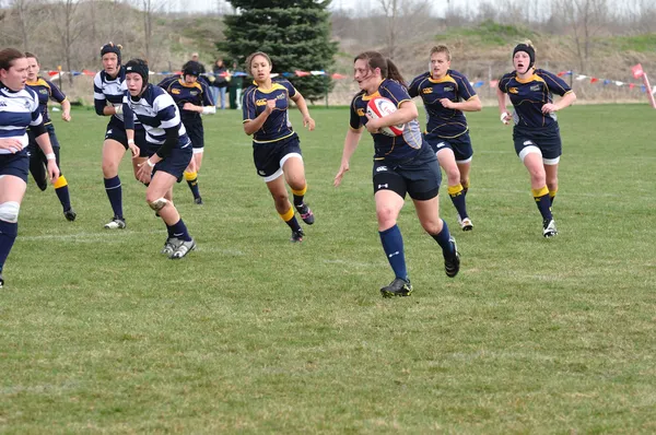 Spieler läuft mit dem Ball in einem Frauen-College-Rugbyspiel — Stockfoto