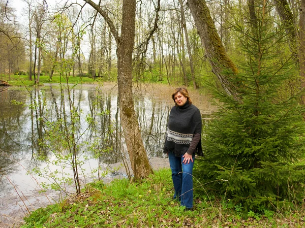 Starší žena na břehu rybníka — Stock fotografie
