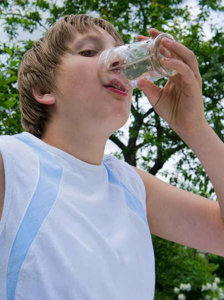 Niño bebe agua de la taza de vidrio — Foto de Stock