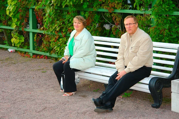 Старшая пара сидит на скамейке — стоковое фото