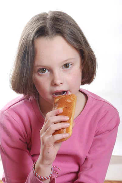 En ung flicka äter en bulle — Stockfoto