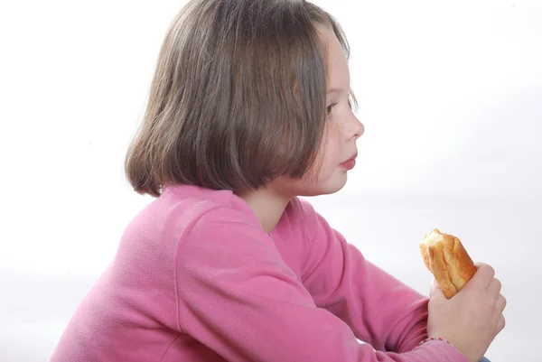 A young girl eating a bun — Stock Photo, Image