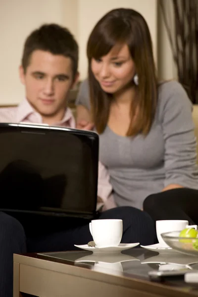 Casal jovem com laptop e café. Foco em xícara de café — Fotografia de Stock