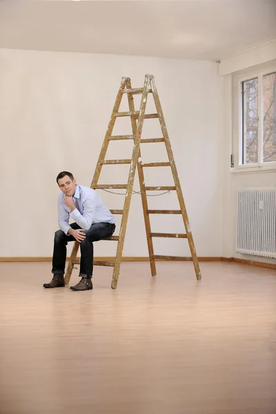 Переезд в новый офис или дом: мужчина сидит на лестнице — стоковое фото