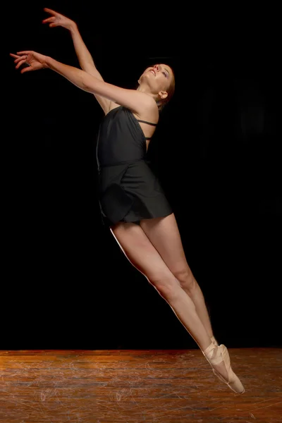 Schöne Ballerina springt im Studio auf schwarzem Hintergrund — Stockfoto