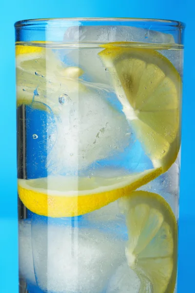 Glas Zitroneneiswasser auf blauem Hintergrund — Stockfoto
