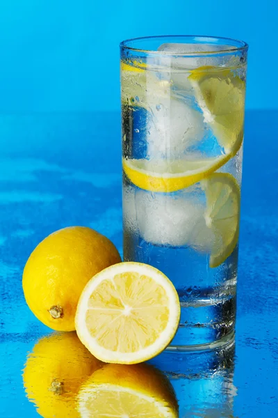 Стакан лимонной ледяной воды на голубом фоне — стоковое фото