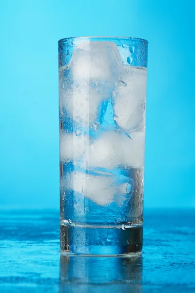 Vaso de agua helada sobre fondo azul — Foto de Stock