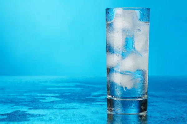 Bicchiere di acqua ghiacciata su sfondo blu — Foto Stock